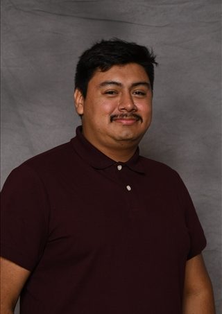 Man in maroon polo shirt, professional headshot portrait.