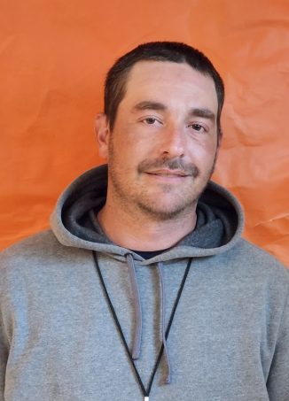 Man wearing gray hoodie against orange background