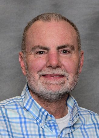 Middle-aged man wearing blue checkered shirt, professional headshot.