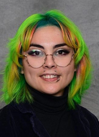 Student with bright green and yellow hair wearing round glasses, smiling.