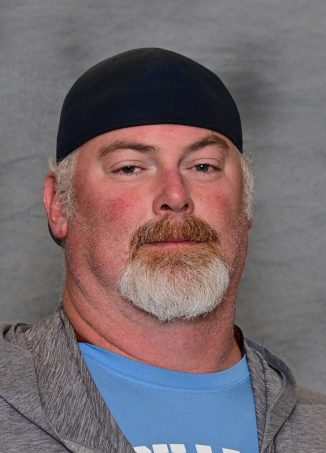 Man wearing black beanie and blue shirt, headshot portrait.
