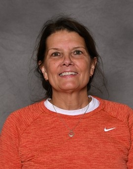 Woman wearing orange Nike shirt, smiling at camera.