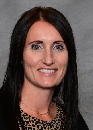 Professional headshot of woman with long dark hair smiling.