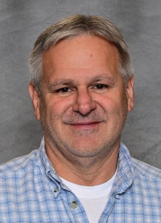 Middle-aged man wearing blue plaid shirt, professional headshot.
