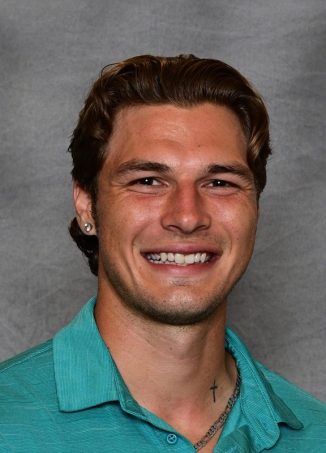 Professional headshot of smiling man in turquoise polo shirt.