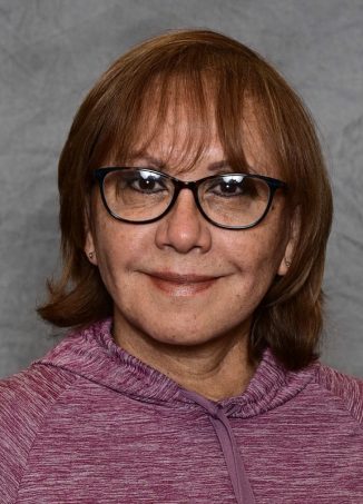 Woman with brown hair, glasses, wearing purple jacket.