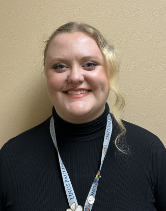 Staff member wearing black turtleneck and lanyard badge smiling.