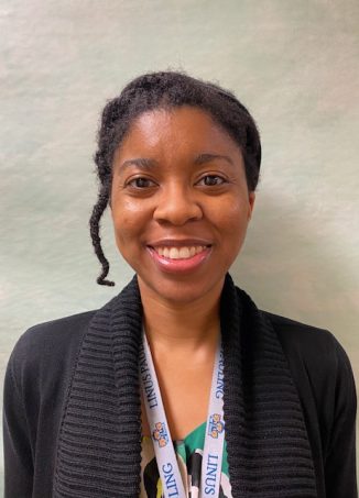 Professional woman wearing black cardigan and lanyard badge smiling.