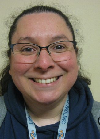 Smiling person wearing glasses and navy blue jacket with lanyard.