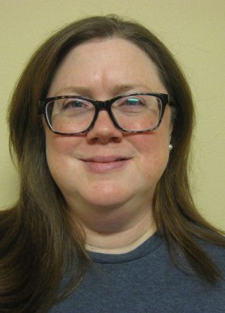 Person wearing glasses and dark blue shirt smiling at camera