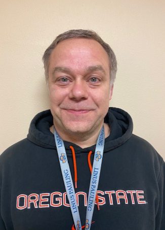 Man wearing Oregon State hoodie and lanyard badge.