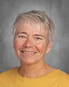 Smiling woman with short gray hair wearing yellow shirt.