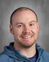 Male staff member with short hair wearing blue hoodie, smiling at camera.