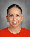 Woman in red shirt against gray background, smiling at camera.