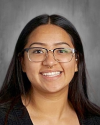 Woman with long dark hair wearing glasses and smiling at camera.
