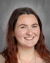 Smiling female student with long reddish-brown hair, portrait photo.