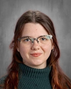 Woman with long reddish-brown hair wearing glasses and turtleneck.